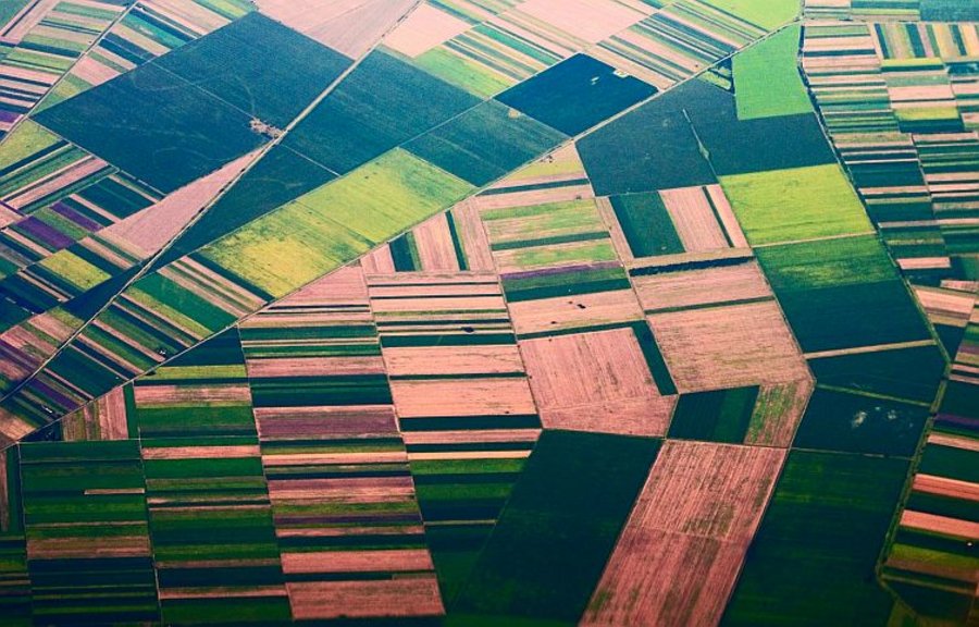 In der Luftbildaufnahme sieht man an den verschiedenfarbigen Rechtecken gut die Unterschiede der landwirtschaftlichen Nutzung. Mausklick führt zur vergrößerten Ansicht